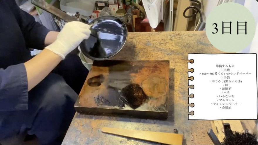 Apply the lacquer coat with the hake — The hake spreads a continuous black lacquer coat across the plate in broad, overlapping strokes.