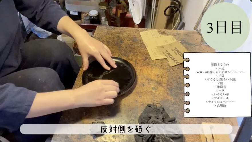 Sand and dust between coats — The maker wet-sands the cured lacquer with a flat abrasive block before the next coat.